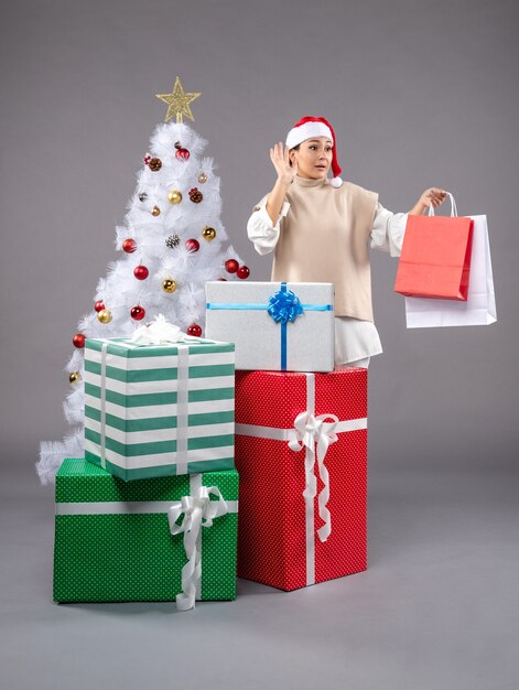 Vista frontal de la mujer joven con regalos navideños en el escritorio de luz regalo de Navidad de año nuevo