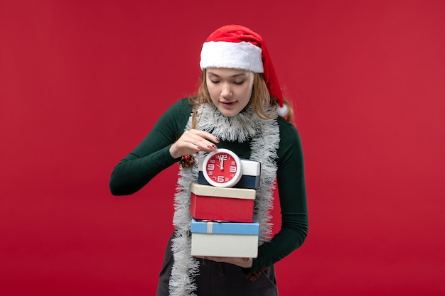 Foto gratuita vista frontal mujer joven con regalos con reloj sobre fondo rojo.