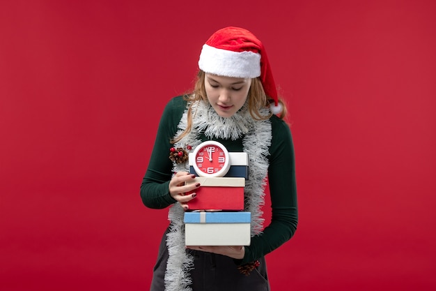 Foto gratuita vista frontal mujer joven con regalos con reloj sobre fondo rojo.