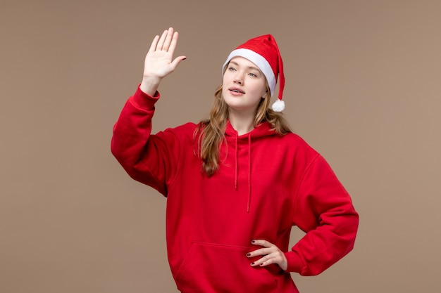 Vista frontal mujer joven saludando sobre un fondo marrón Navidad emoción vacaciones