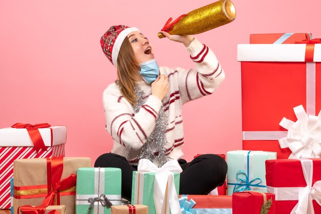 Vista frontal mujer joven sentada alrededor de regalos y celebrando