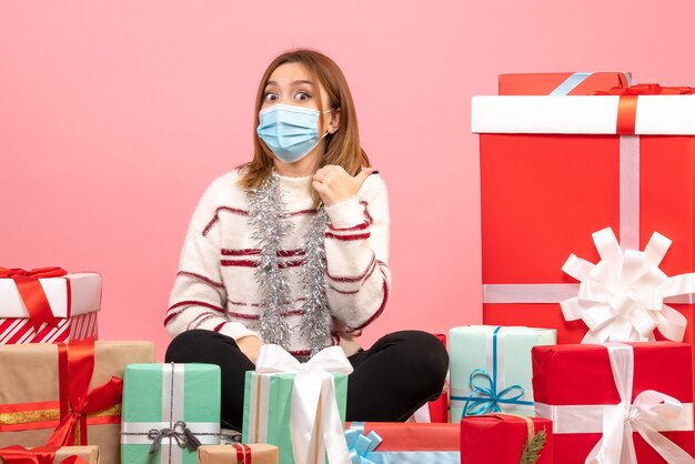 Vista frontal mujer joven sentada alrededor de regalos de Navidad