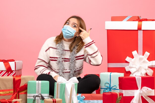 Vista frontal mujer joven sentada alrededor de regalos de Navidad