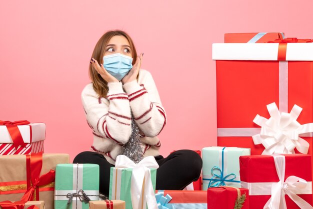 Vista frontal mujer joven sentada alrededor de regalos de Navidad