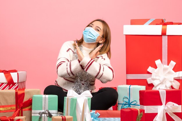 Vista frontal mujer joven sentada alrededor de regalos de Navidad