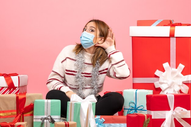 Vista frontal mujer joven sentada alrededor de regalos de Navidad