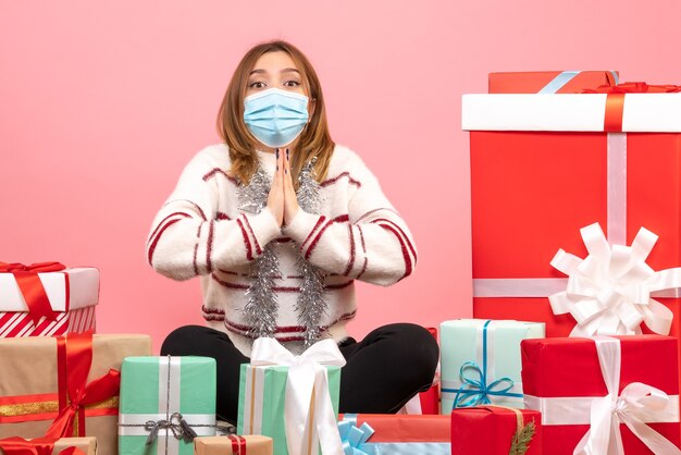 Vista frontal mujer joven sentada alrededor de regalos de Navidad