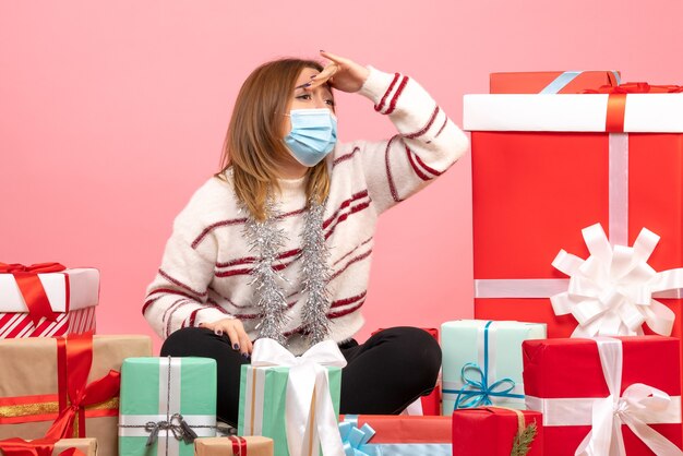 Vista frontal mujer joven sentada alrededor de regalos de Navidad