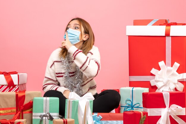 Vista frontal mujer joven sentada alrededor de regalos de Navidad