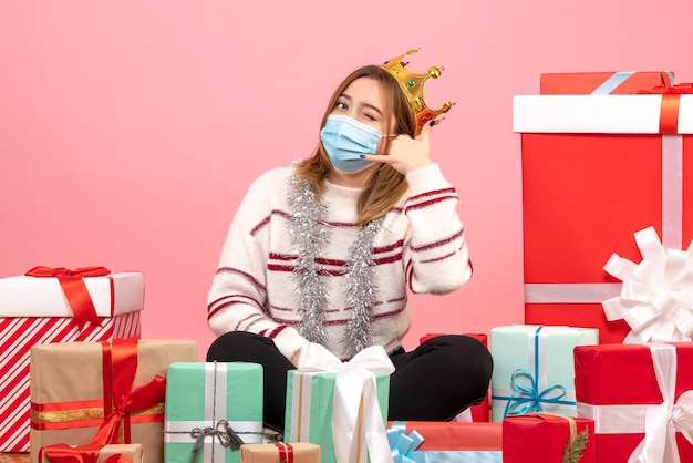 Vista frontal mujer joven sentada alrededor de regalos de Navidad