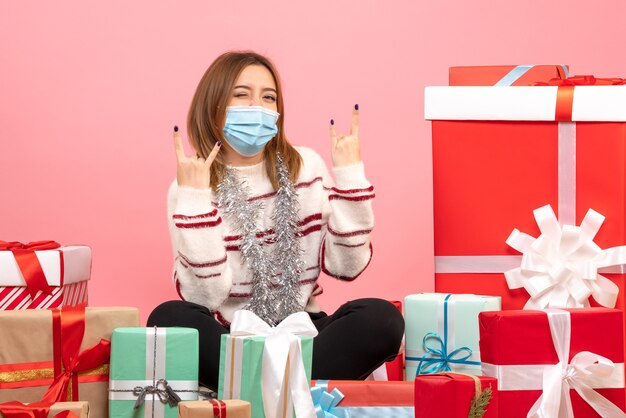 Vista frontal mujer joven sentada alrededor de regalos de Navidad