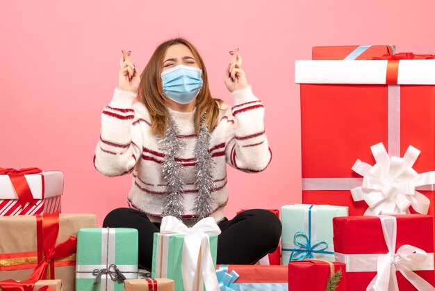 Vista frontal mujer joven sentada alrededor de regalos de Navidad