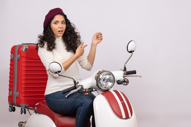 Vista frontal mujer joven sentada en bicicleta sobre fondo blanco velocidad del vehículo color vacaciones motocicleta carretera ciudad