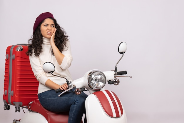 Vista frontal mujer joven sentada en bicicleta sobre fondo blanco velocidad del vehículo color vacaciones motocicleta carretera mujer