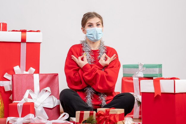 Vista frontal mujer joven sentada con regalos de Navidad en máscara