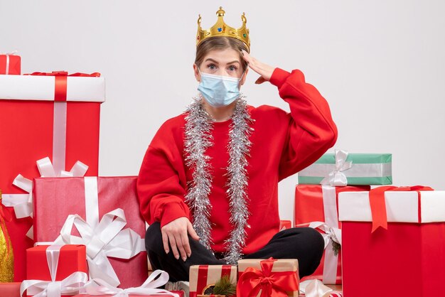 Foto gratuita vista frontal mujer joven sentada con regalos de navidad en máscara