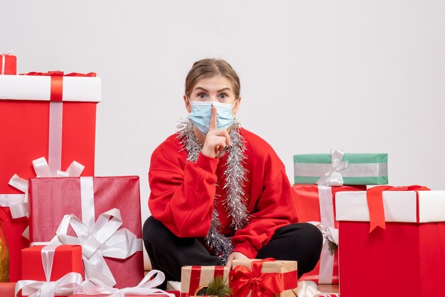 Vista frontal mujer joven sentada con regalos de Navidad en máscara