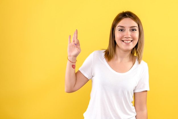 Vista frontal, de, mujer joven, simplemente, sonriente, en, pared amarilla