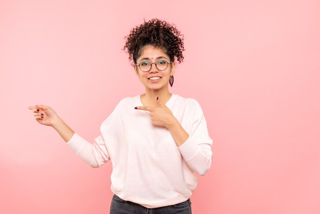 Vista frontal, de, mujer joven, simplemente, sonriente, en, pared rosa