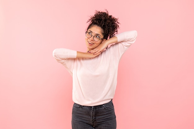 Vista frontal de la mujer joven soñando en la pared rosa