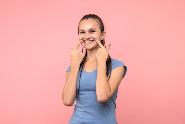 Vista frontal de la mujer joven sonriendo en rosa