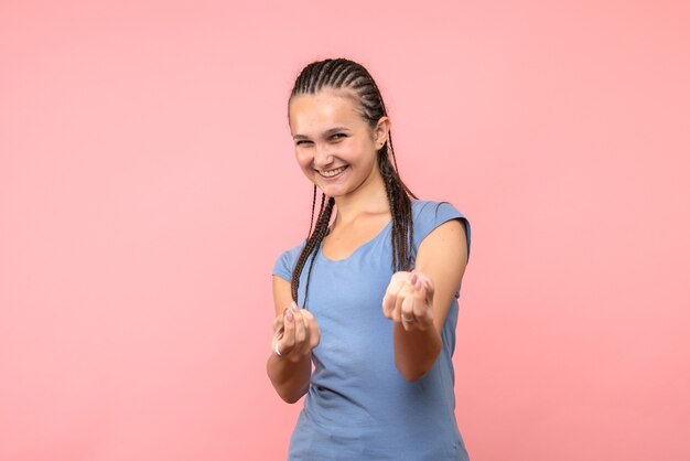 Vista frontal de la mujer joven sonriendo en rosa