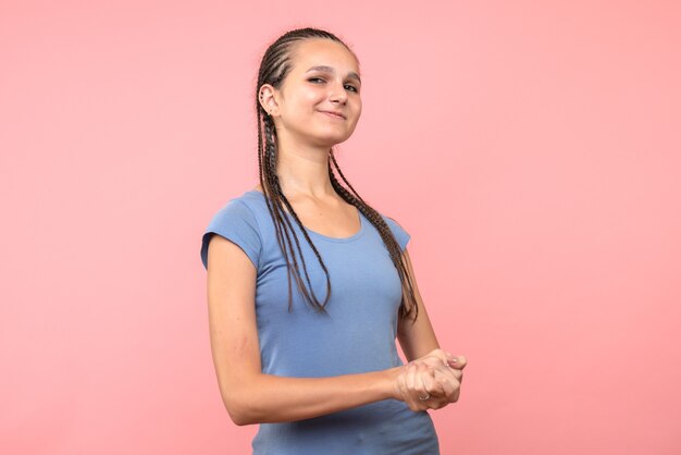 Vista frontal de la mujer joven sonriendo en rosa