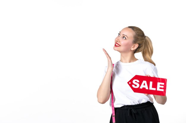 Vista frontal mujer joven sonriente con cinta métrica y placa de venta sobre fondo blanco perder medición adelgazamiento compras torso cadera piel cuerpo cintura centro comercial