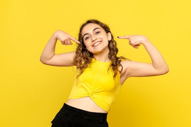 Vista frontal, de, mujer joven, sonriente, en, pared amarilla