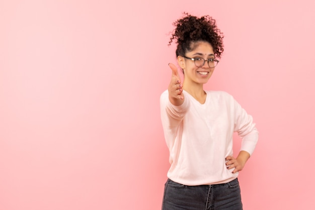 Foto gratuita vista frontal, de, mujer joven, sonriente, en, pared rosa