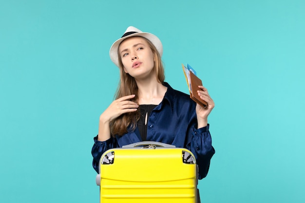 Vista frontal mujer joven sosteniendo boletos y preparándose para las vacaciones en el fondo azul viaje en avión viaje por mar vacaciones viaje