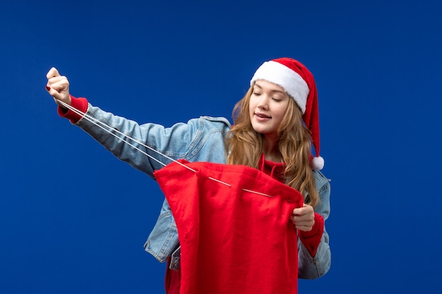 Foto gratuita vista frontal mujer joven sosteniendo la bolsa con regalos sobre un fondo azul emoción vacaciones de navidad