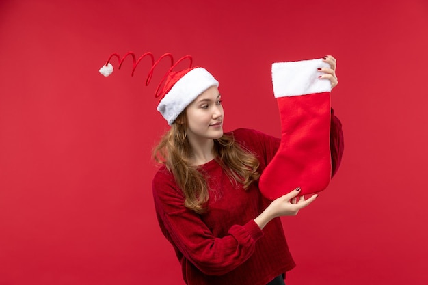 Vista frontal mujer joven sosteniendo calcetín rojo de Navidad, mujer roja de vacaciones