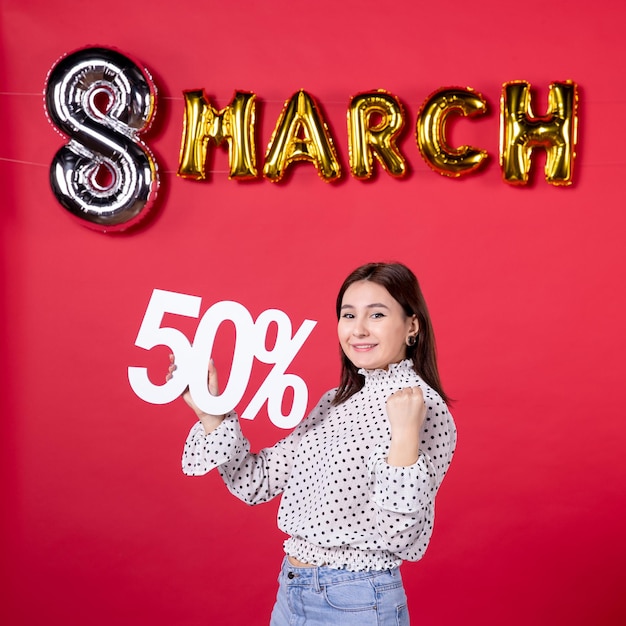 Vista frontal mujer joven sosteniendo la escritura sobre fondo rojo compras igualdad cariñosa belleza centro comercial vacaciones mujer dinero