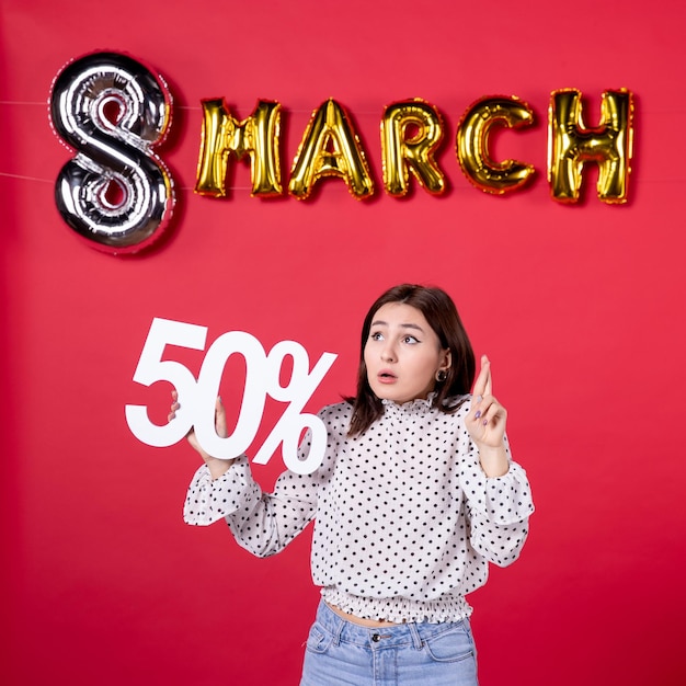 Foto gratuita vista frontal mujer joven sosteniendo la escritura sobre fondo rojo vacaciones compras igualdad cariñosa belleza mujer dinero moda