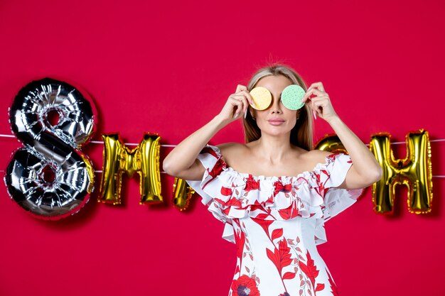 Vista frontal mujer joven sosteniendo esponjas de colores para desmaquillarse en marzo decorado glamour rojo