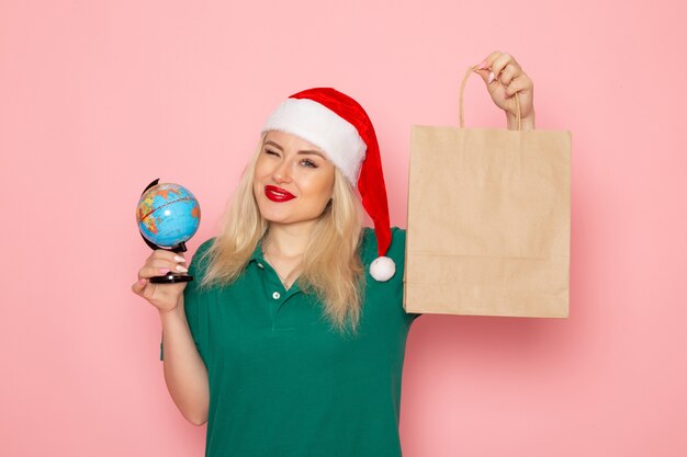 Vista frontal mujer joven sosteniendo globo y regalo de Navidad en la pared rosa modelo de fotografía de Navidad mujer vacaciones de año nuevo