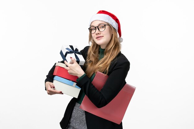 Vista frontal mujer joven sosteniendo regalos navideños en el libro de regalo de escritorio blanco año nuevo