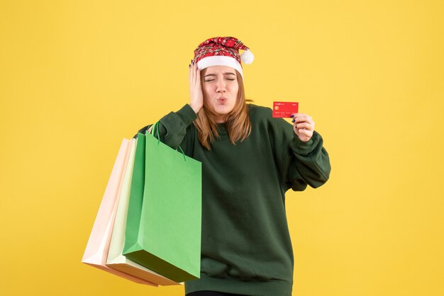 Vista frontal mujer joven con tarjeta bancaria y paquetes de compras