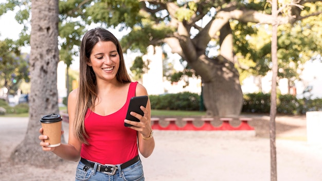 Vista frontal, mujer joven, tenencia, café, y, teléfono