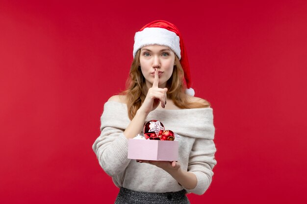 Vista frontal, de, mujer joven, tenencia, navidad, juguetes, en, rojo