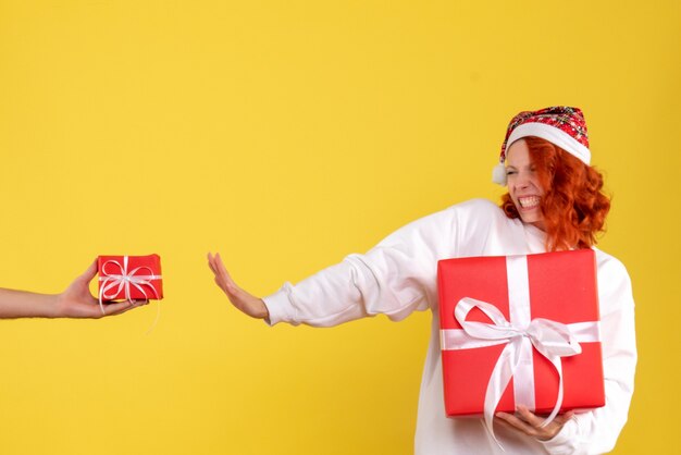 Vista frontal, de, mujer joven, tenencia, navidad, presente, en, pared amarilla