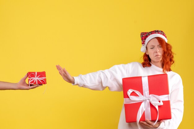 Vista frontal, de, mujer joven, tenencia, navidad, presente, en, pared amarilla