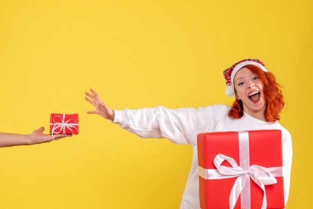 Vista frontal, de, mujer joven, tenencia, navidad, presente, en, pared amarilla