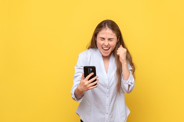 Vista frontal, de, mujer joven, tenencia, teléfono, y, regocijo