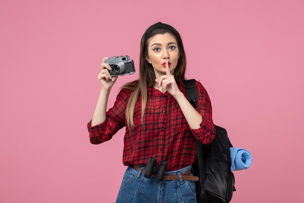 Vista frontal mujer joven tomando una foto con la cámara en el color de la foto de la mujer de fondo rosa