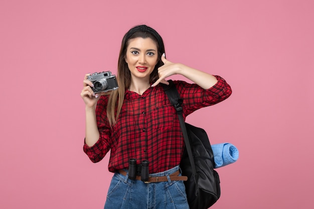 Vista frontal mujer joven tomando una foto con la cámara en el color de la foto de la mujer de fondo rosa