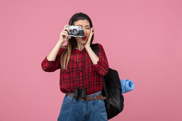 Vista frontal mujer joven tomando una foto con la cámara en el color de la foto de la mujer de fondo rosa