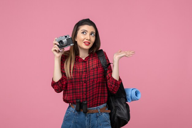 Vista frontal mujer joven tomando una foto con la cámara en el color de la mujer de la foto de fondo rosa