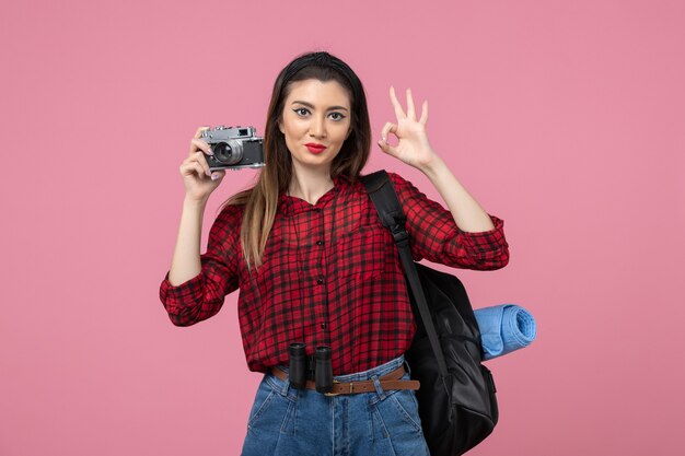 Vista frontal mujer joven tomando una foto con la cámara en el color rosa de la mujer de la foto del escritorio